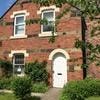 Linden Dental Cottage in Ashington - a brick building with a white door and neatly kept garden