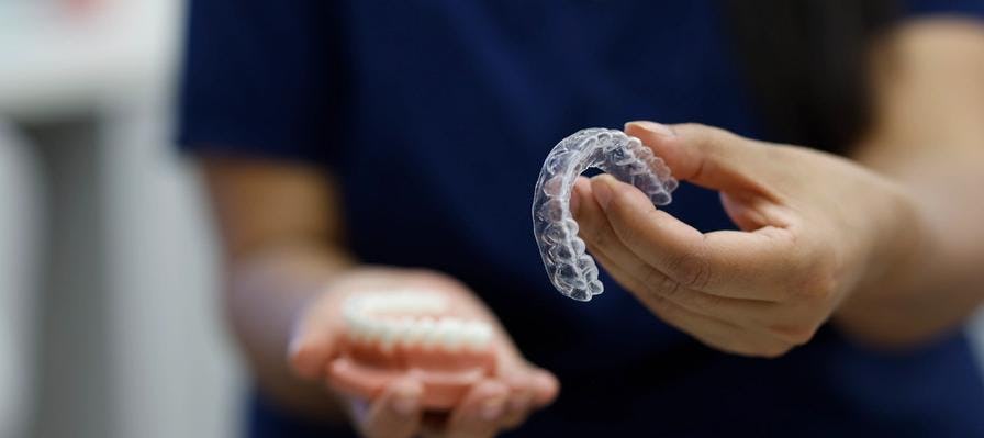 An orthodontist holds out Invisalign braces towards the camera