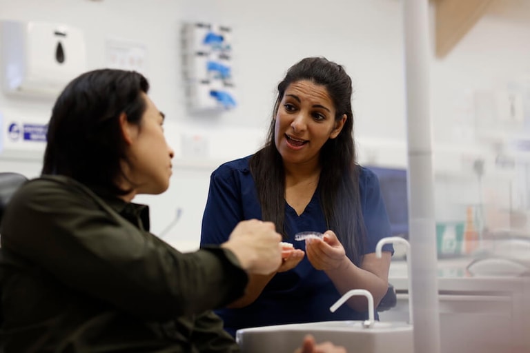 Orthodontist passing a patient their Invisible Aligners