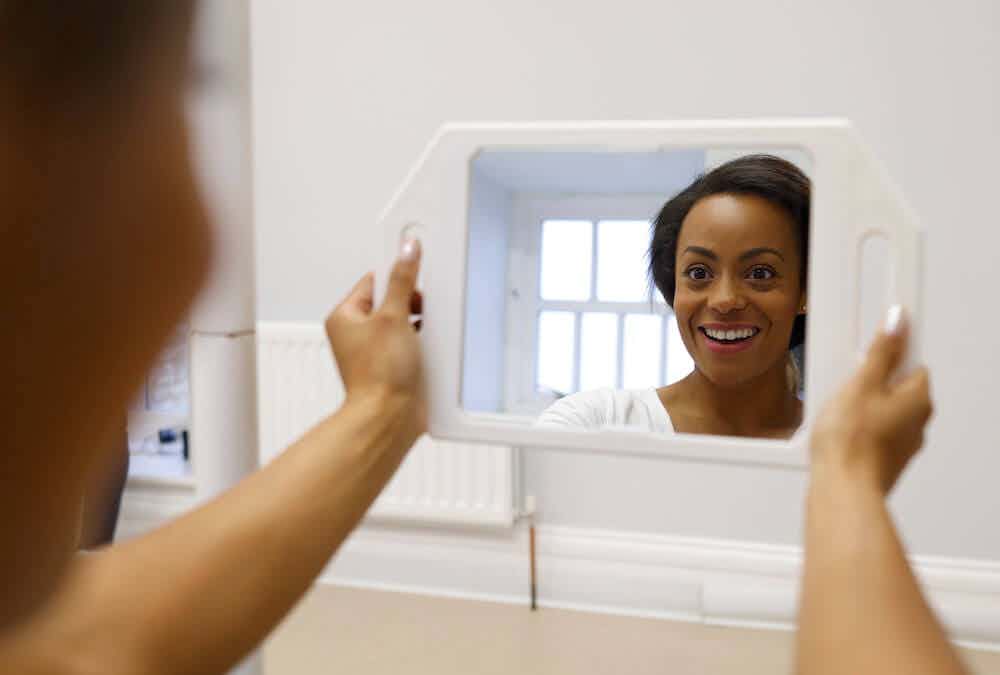An invisslign patient looks at her smile in the mirror after treatment