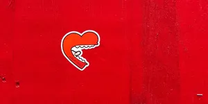 A heart shaped mouth with white teeth and long tongue, graffiti on a red wall