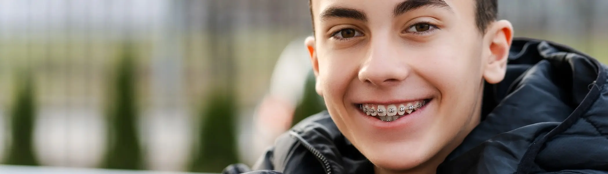 A teenager with fixed braces smiles, soft focus portrait