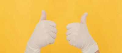 Latex-gloved hands give the thumbs up