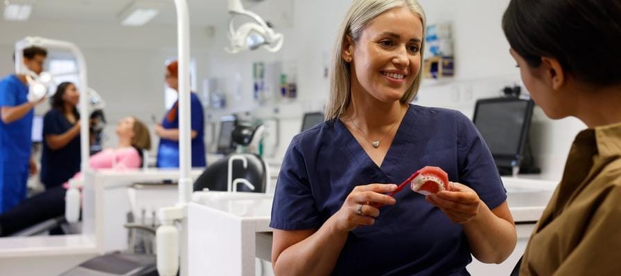 A close up on an orthodontist inspecting a mouth with fixed braces and colourful bracket modules
