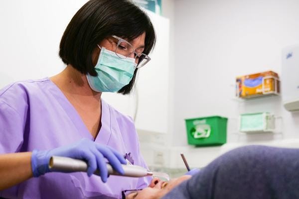 An orthodontist with face mask examines a patient in a dental chair at Windmill Gateshead Practice