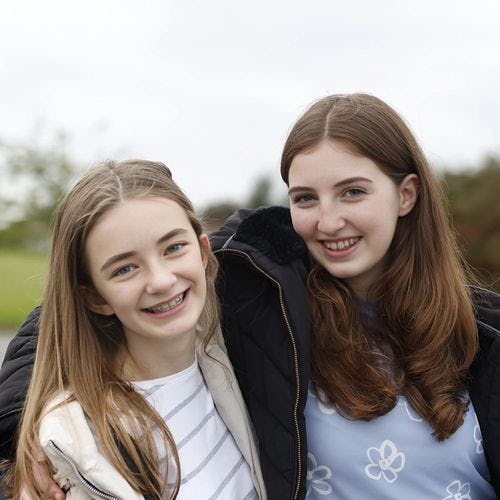2 teenagers with fixed metal braces smile at the camera